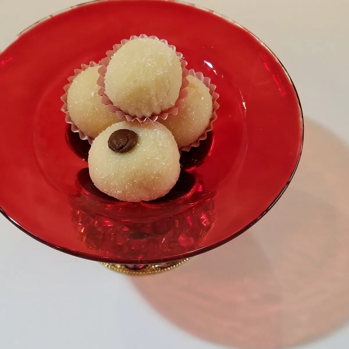 A tray of glossy brigadeiros rolled in chocolate sprinkles in paper cups