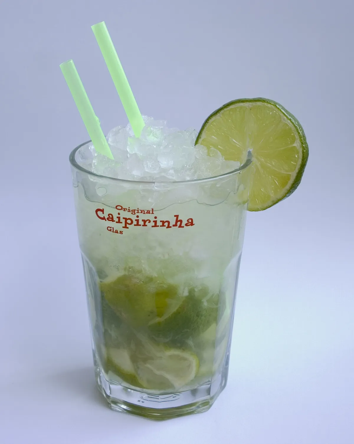 A caipirinha packed with crushed lime and ice in a short tumbler
