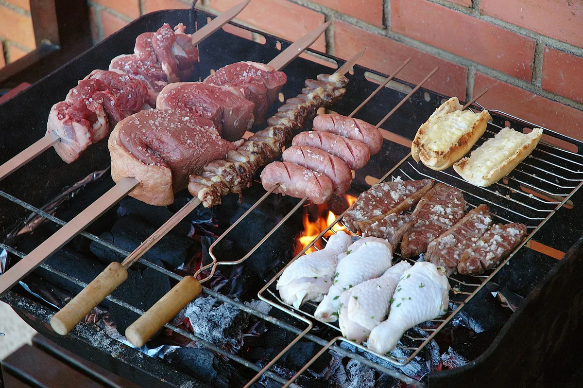 A thick cap of picanha sizzling on a skewer over glowing churrasco coals