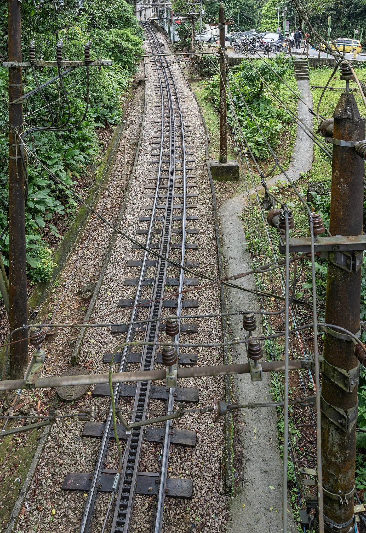 The red Corcovado cog railway train climbing steeply through dense green rainforest