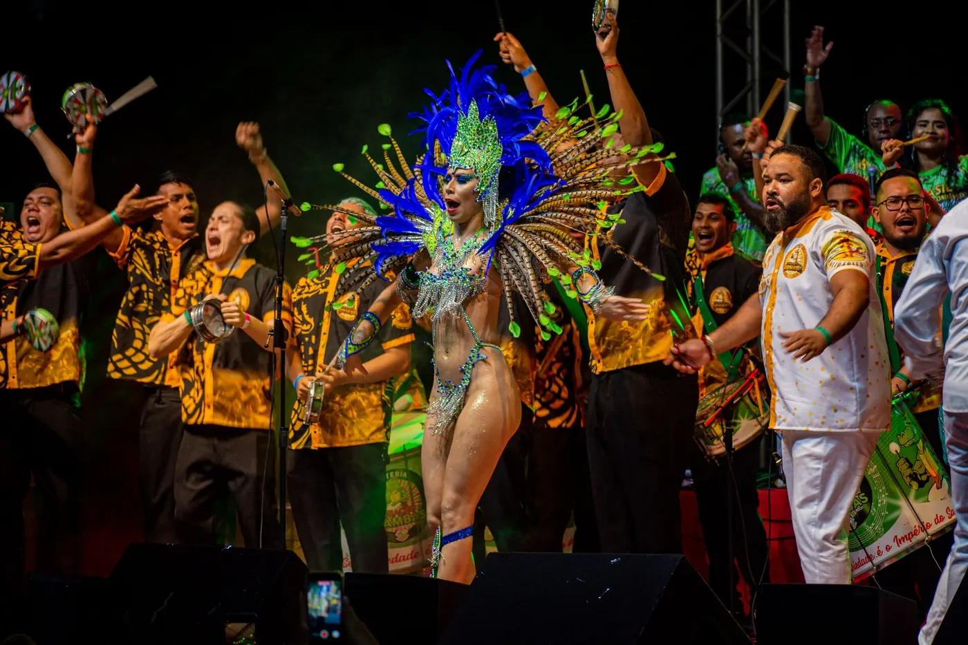 Dozens of drummers in matching costume pound surdos and tamborims in a samba school bateria