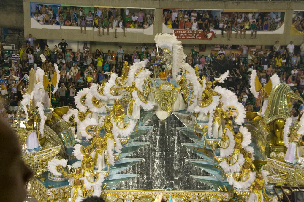 A samba school in full costume parades down the floodlit Sambadrome avenue as packed grandstands cheer