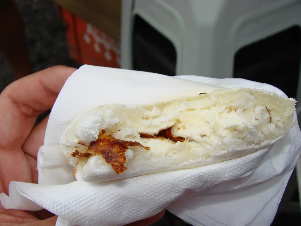 A folded white tapioca crepe oozing melted cheese on a griddle
