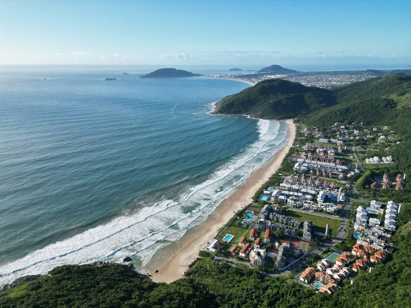 Aerial view of a curved beach and green headland in Florianópolis