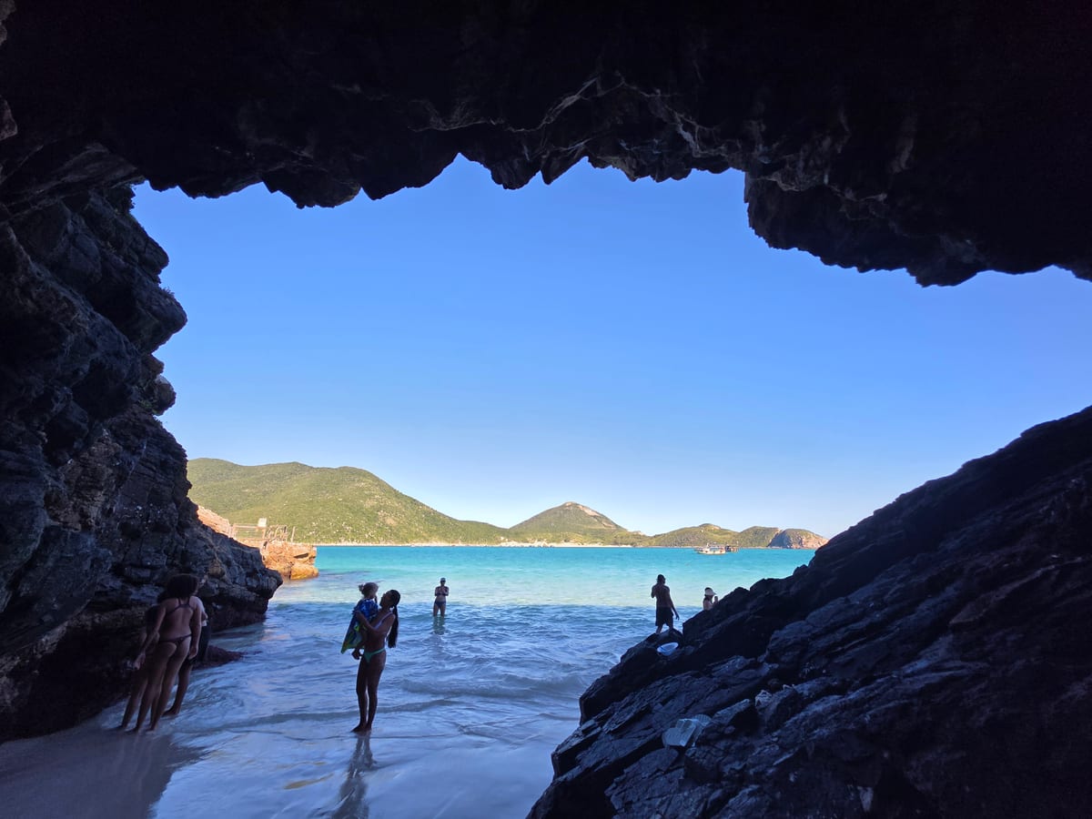 Travellers walking into a sea cave on a beach near Rio de Janeiro
