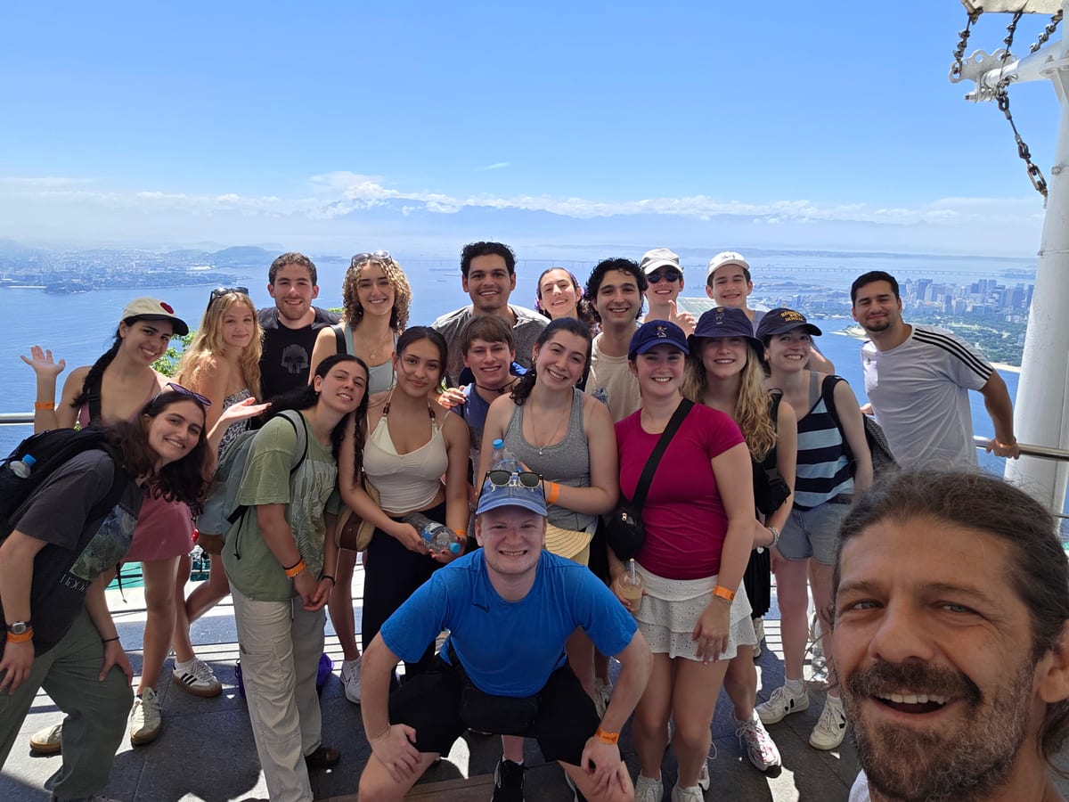 A large tour group together on a boat with the Rio de Janeiro skyline behind