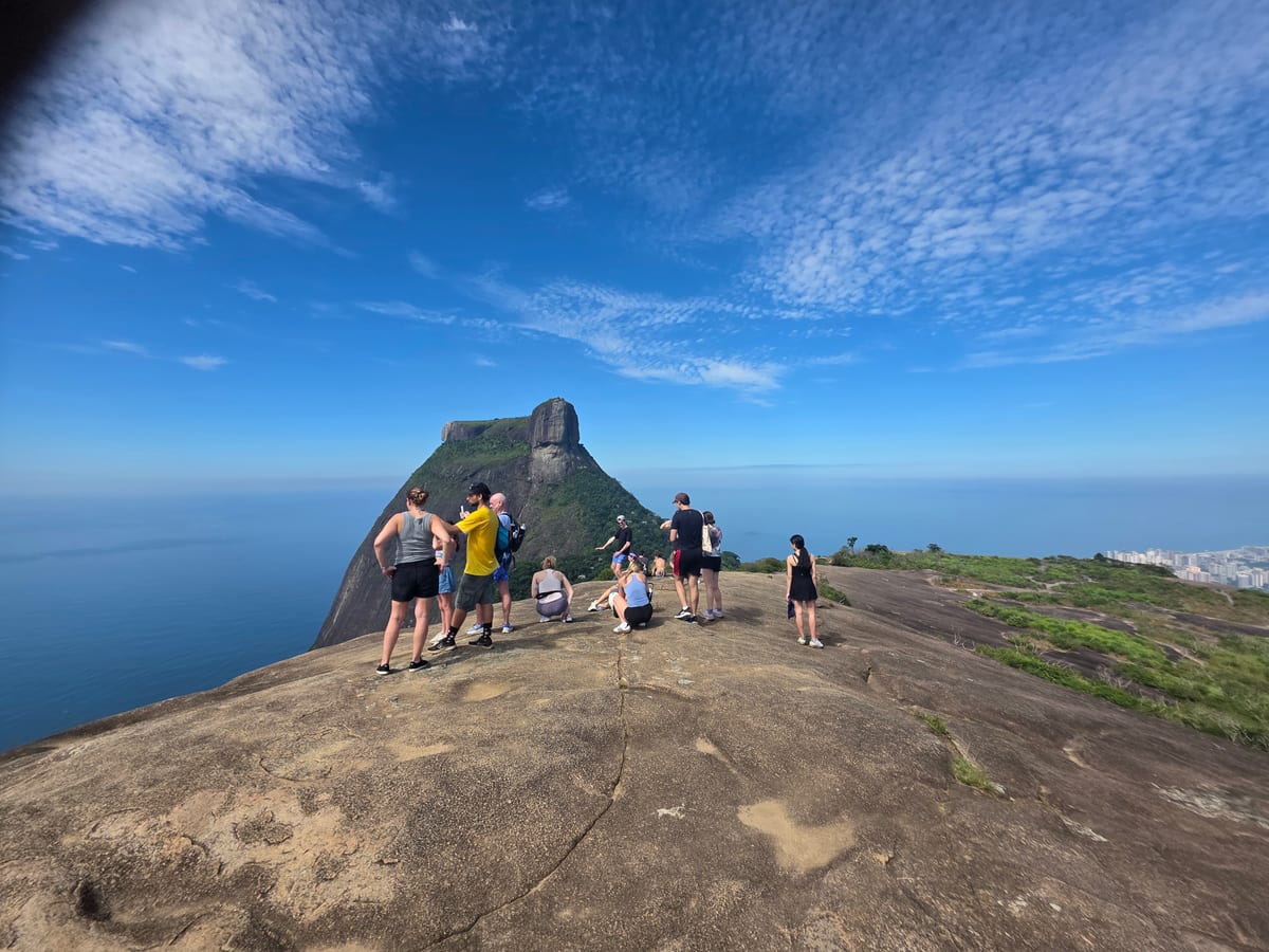 Hikers on a granite summit overlooking Pedra da Gávea, Rio de Janeiro